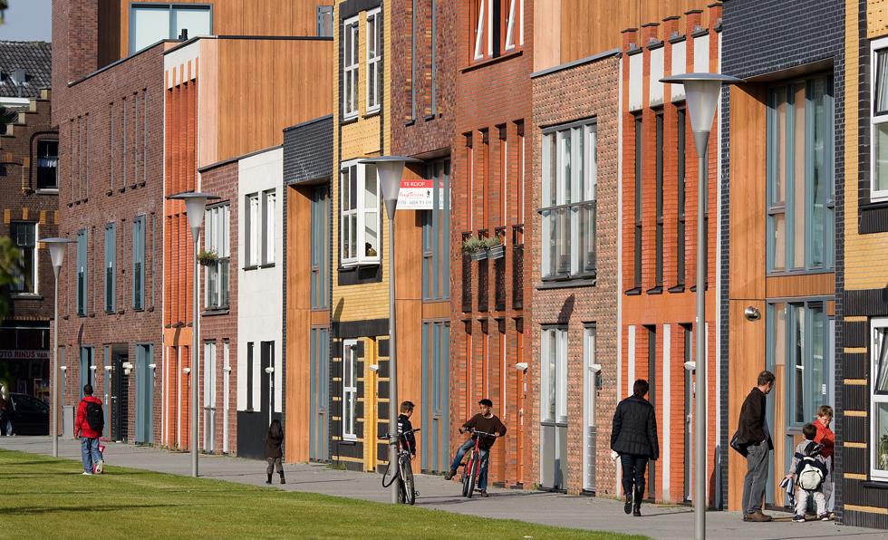 Photo of a street with houses and people walking by